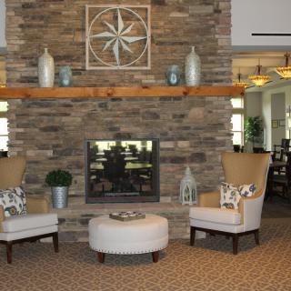 A cozy living room featuring a stone fireplace, comfortable chairs, and stylish decor.