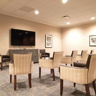 A conference room with arranged chairs and a TV screen, ready for a meeting.