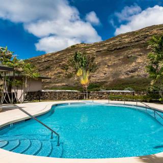 A tranquil swimming pool with a stunning mountain backdrop under a clear blue sky.