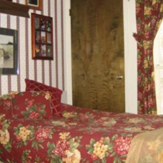 A cozy bedroom with floral bedding and striped wallpaper, featuring traditional decor elements.