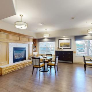 A cozy living room with a wooden floor, featuring a fireplace, seating area, and elegant decor.