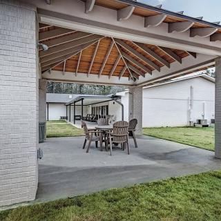 A covered outdoor patio featuring a dining set with a wooden ceiling and an open yard.