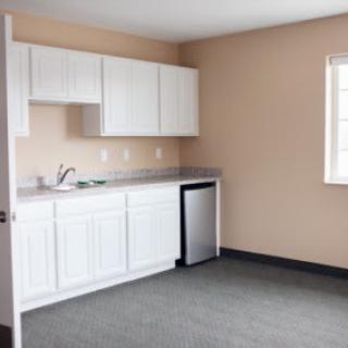A compact kitchen area with white cabinets and a small refrigerator.