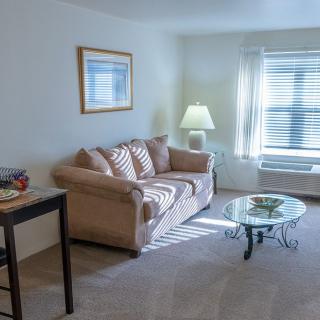 A cozy living room with a sofa, coffee table, and lamp by the window.