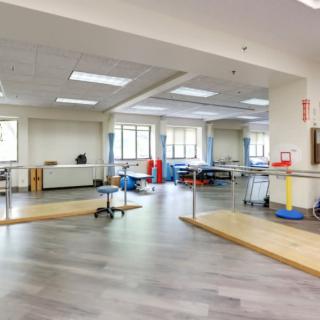 A spacious rehabilitation center equipped with exercise equipment and parallel bars for physical therapy.