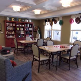 A cozy community dining area with tables, chairs, and decorative hats on the walls.