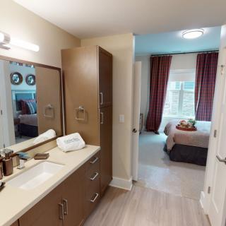A modern bathroom with a view into a cozy bedroom featuring elegant decor and natural lighting.