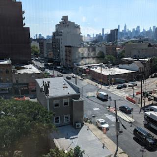 A bustling urban scene showcasing buildings, streets, and vehicles under a clear blue sky.