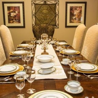 An elegantly set dining table ready for a formal gathering, featuring fine dinnerware and glassware.