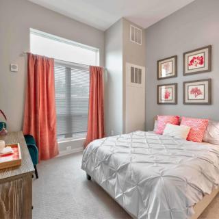 A cozy bedroom with soft pink accents and decorative artwork on the wall.