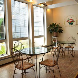 A cozy cafe interior with natural light, featuring glass tables and metal chairs.