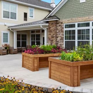 A charming residential patio featuring raised planter boxes filled with vibrant flowers.