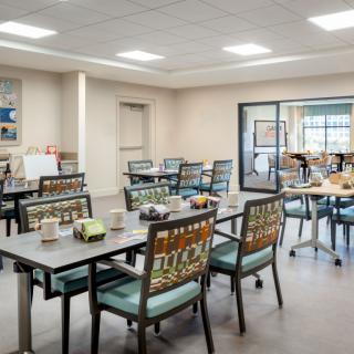 A well-lit community dining area with arranged tables and chairs.