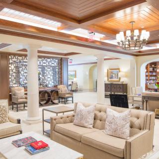 A luxurious and elegantly designed living room with plush sofas, a chandelier, decorative columns, and a bookshelf.