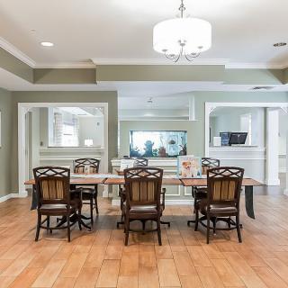 A modern dining room with a wooden table and upholstered chairs, illuminated by a contemporary chandelier.