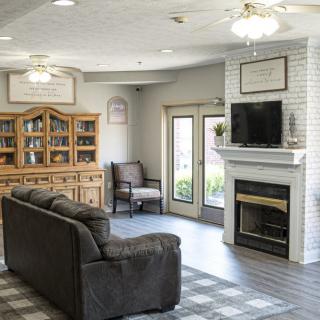 A cozy living room with a sofa, armchair, and a fireplace topped with a television.