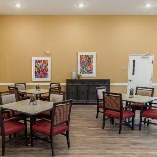 A cozy dining area with several tables and chairs, adorned with colorful artwork on the walls.