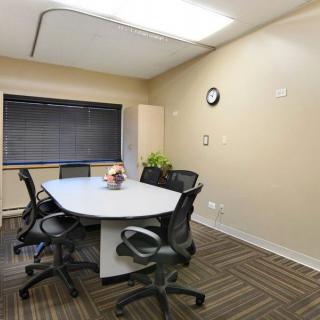 A small conference room with a meeting table, chairs, and a clock on the wall.