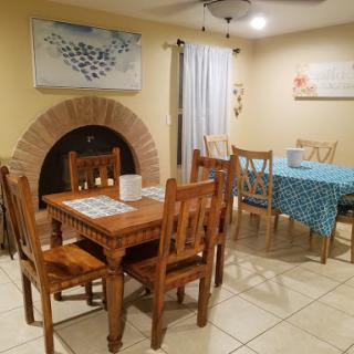 A cozy dining area featuring wooden furniture, a fireplace, and bright decor.