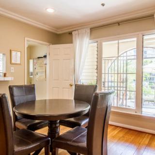 A cozy dining room with a round table and four chairs, featuring large windows that let in natural light.