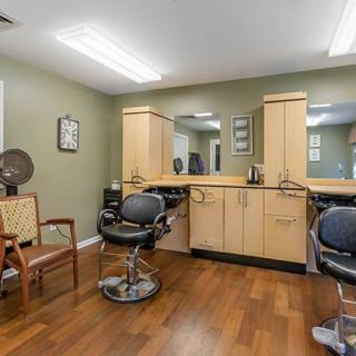 An interior view of a hair salon with chairs, mirrors, and cabinetry.