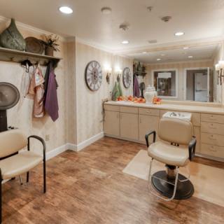 A cozy salon interior featuring a stylist's chair, mirrors, and decorative elements.