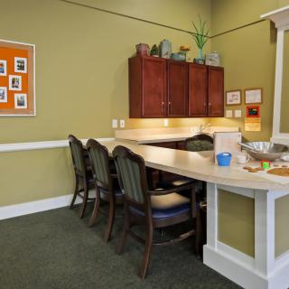 A small office meeting area with chairs, a counter, cabinets, and a notice board.