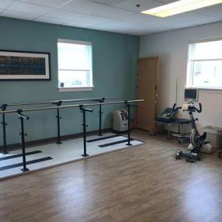 A spacious rehabilitation room equipped with ballet bars and exercise equipment, designed for physical therapy sessions.