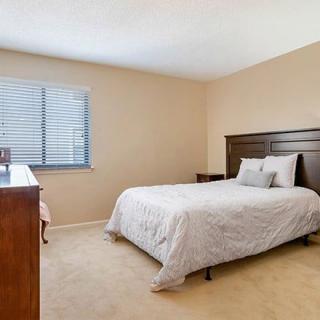 A cozy bedroom with a bed, dresser, and window with blinds.