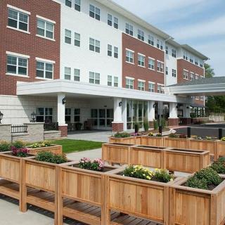 A modern residential building with wooden planters and landscaping in the foreground.