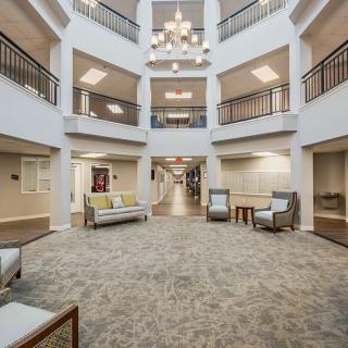 A spacious lobby with multiple seating areas, a central chandelier, and surrounding balconies.