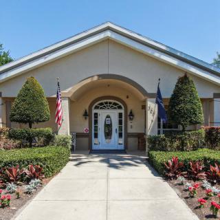 A symmetrical building entrance with a well-maintained garden and flags on either side.