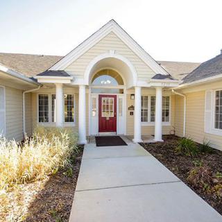 A welcoming residential home entrance with a red front door and white columns.