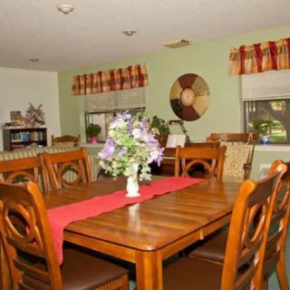 A cozy dining room with a wooden table, chairs, and a floral centerpiece.