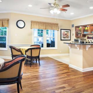 A cozy living space with wooden flooring, featuring a small dining area and bar counter.