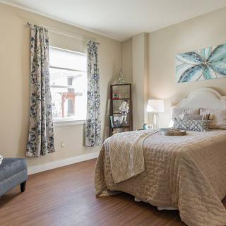 A cozy bedroom with elegant decor featuring a bed, patterned curtains, and artwork on the wall.