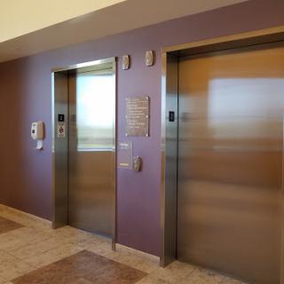 A view of two modern elevators in a building with a stylish purple wall.