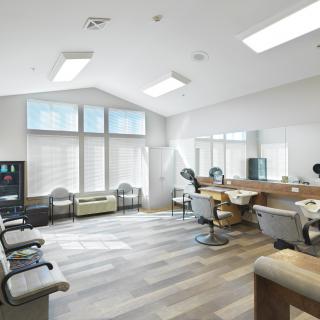 Modern barbershop interior with a spacious waiting area and multiple barber chairs.