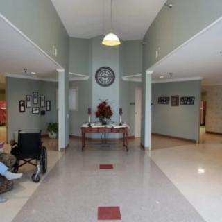 A lobby area featuring a clock, decorative flowers, and accessible design with a person in a wheelchair.