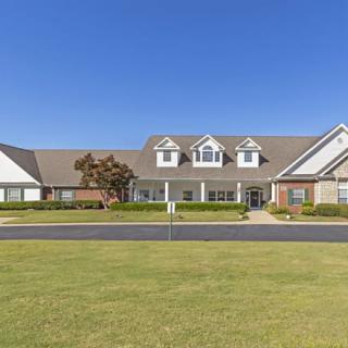 A large residential house with a well-maintained lawn under a clear blue sky.