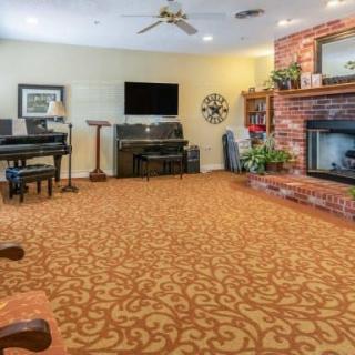 A cozy living room with a brick fireplace, piano, and television.