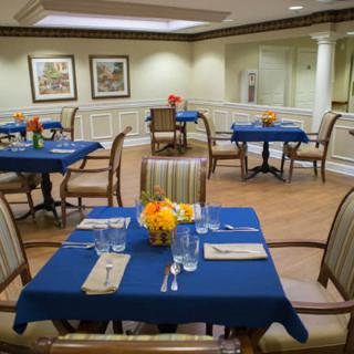 A cozy dining room with blue tablecloths and floral centerpieces.