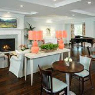 A cozy living room featuring elegant furniture, a grand piano, and a fireplace.