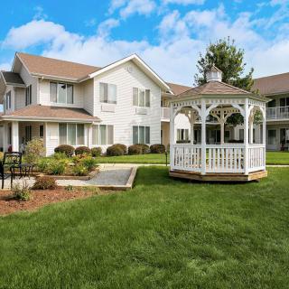 A residential building with a well-maintained lawn and a charming gazebo on a sunny day.
