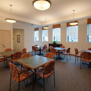 A well-lit dining room featuring multiple tables and chairs with patterned upholstery.