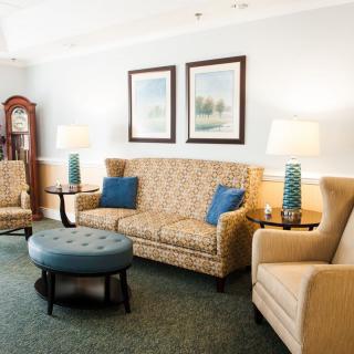 A cozy, well-furnished living room featuring a patterned sofa, two armchairs, a coffee table, and decorative lamps.