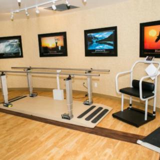 A rehabilitation room equipped with parallel bars and exercise equipment for physical therapy.