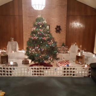 A festive Christmas tree surrounded by presents and holiday decorations in a cozy room.