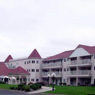 A multi-story residential building with red roofs and balconies set against a cloudy sky.