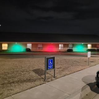 A building illuminated with green and red lights at night, highlighting a welcoming atmosphere.